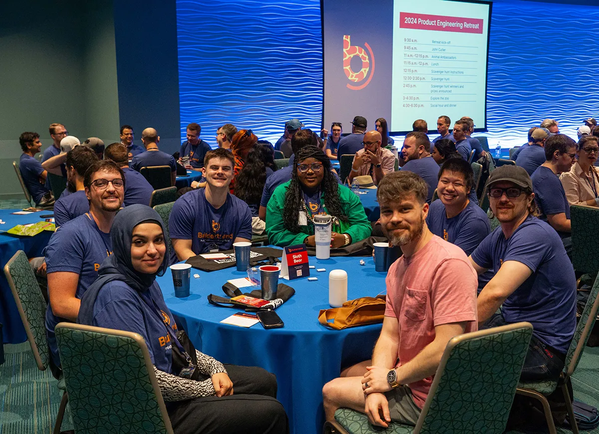 Group of Buildertrend team members seated at round tables during a product engineering retreat and presentation.