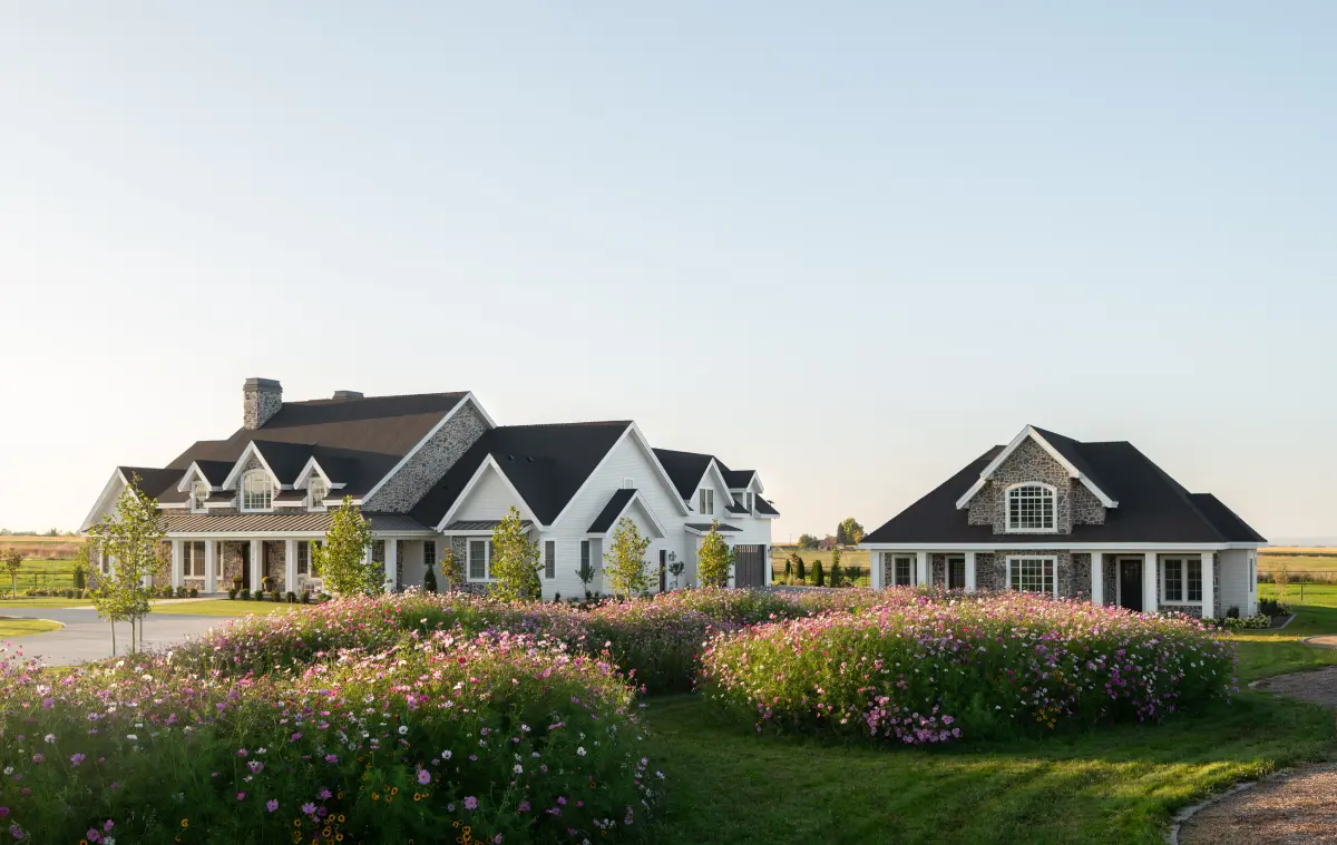 Buildertrend university case study thumbnail: Luxury custom home with white siding and stone accents surrounded by landscaped gardens and open green space.