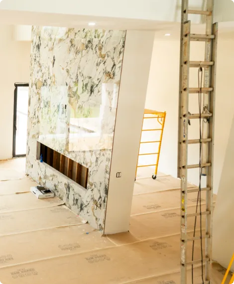 Home interior under construction featuring marble floor to ceiling fireplace