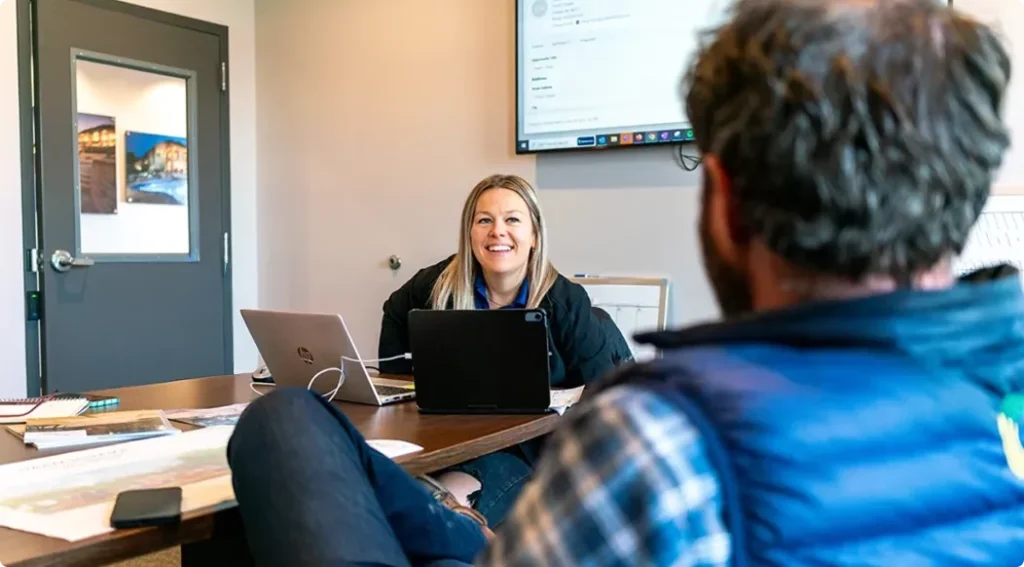 Two colleagues in an office together smiling and working together