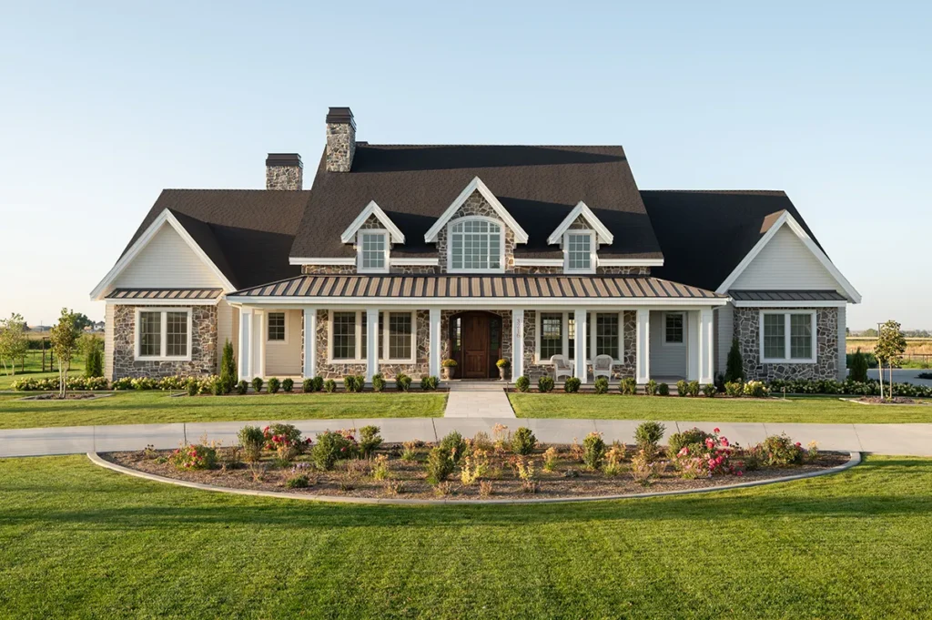 Large custom home exterior with stone and white siding, covered front porch, and landscaped lawn.