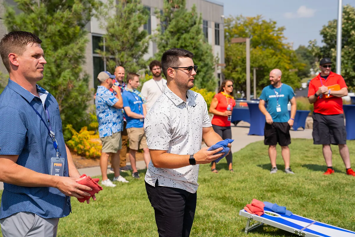 People participating in an outdoor lawn game activity during a company event.