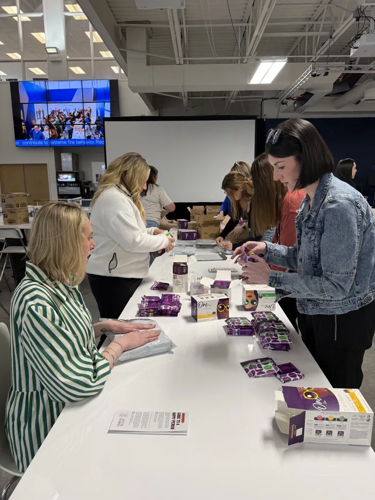 Group assembling care packages at a long table with supplies and boxed items during a volunteer event.