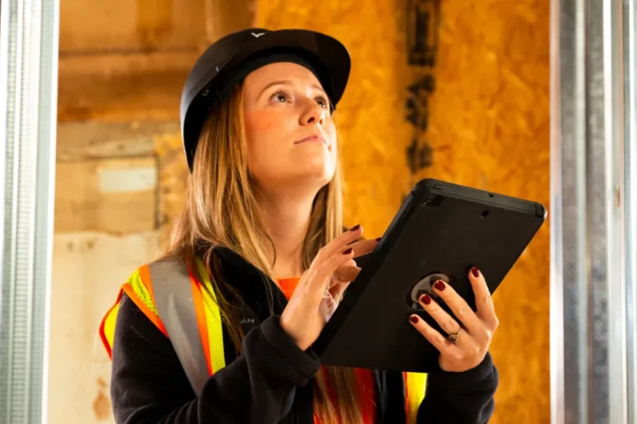 woman holding a tablet inside of unfinished construction