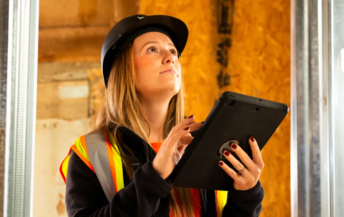 woman holding a tablet inside of unfinished construction