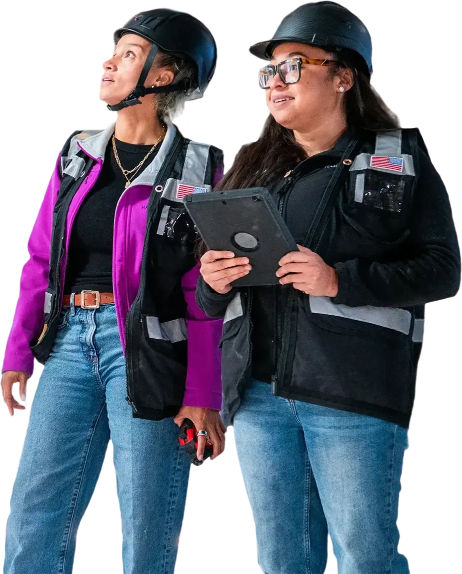 Two women in hard hats reviewing tablet