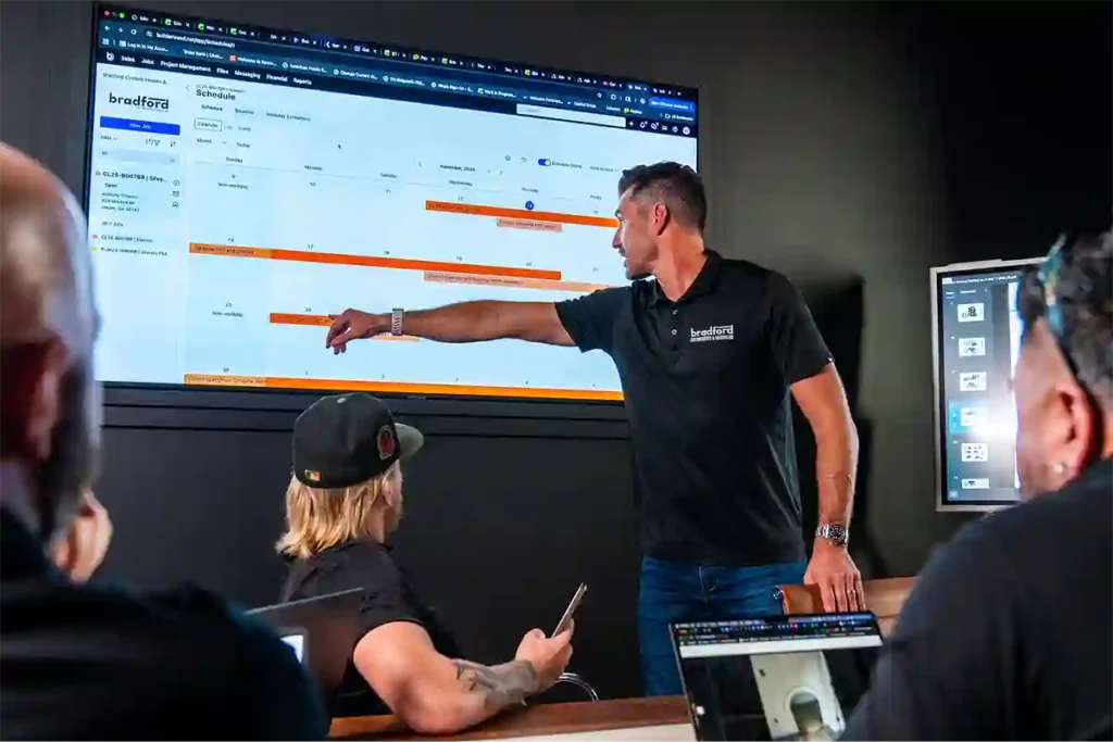 Bradford Custom Homes team looking at a Buildertrend screen during a team meeting