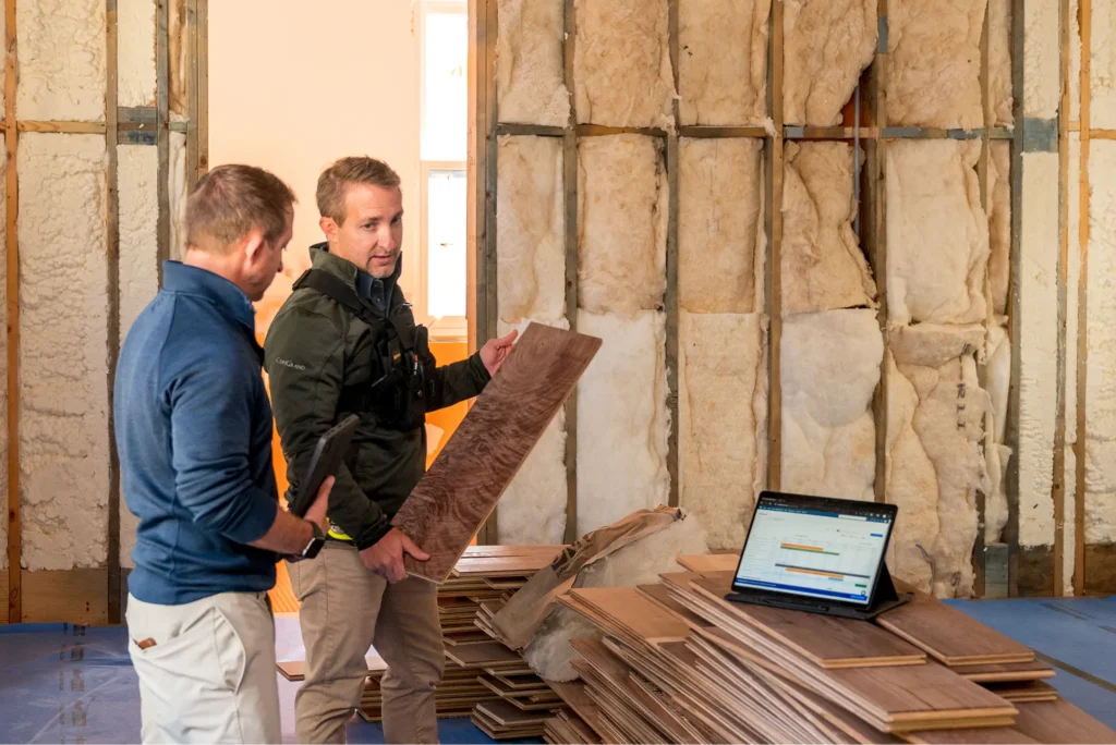 Two men looking at wood planks at a construction site