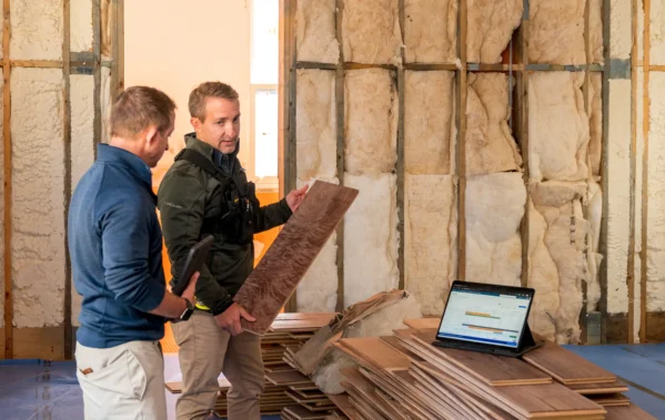 Two men looking at wood planks at a construction site