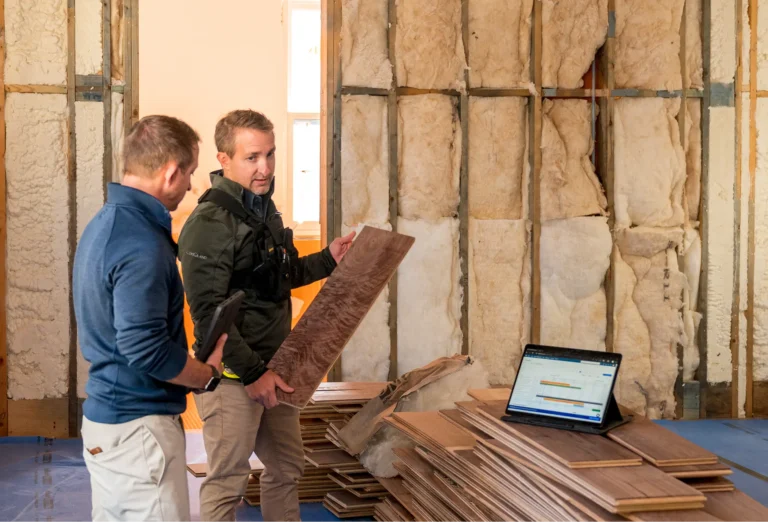 Two men looking at wood planks at a construction site