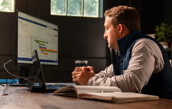A man in his office looking at a Buildertrend Gantt chart