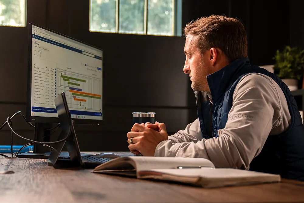 A man in his office looking at a Buildertrend Gantt chart