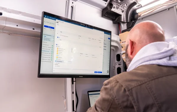 Man on job site looking at Buildertrend software on monitor