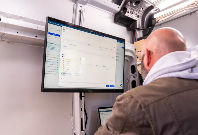 Man on job site looking at Buildertrend software on monitor