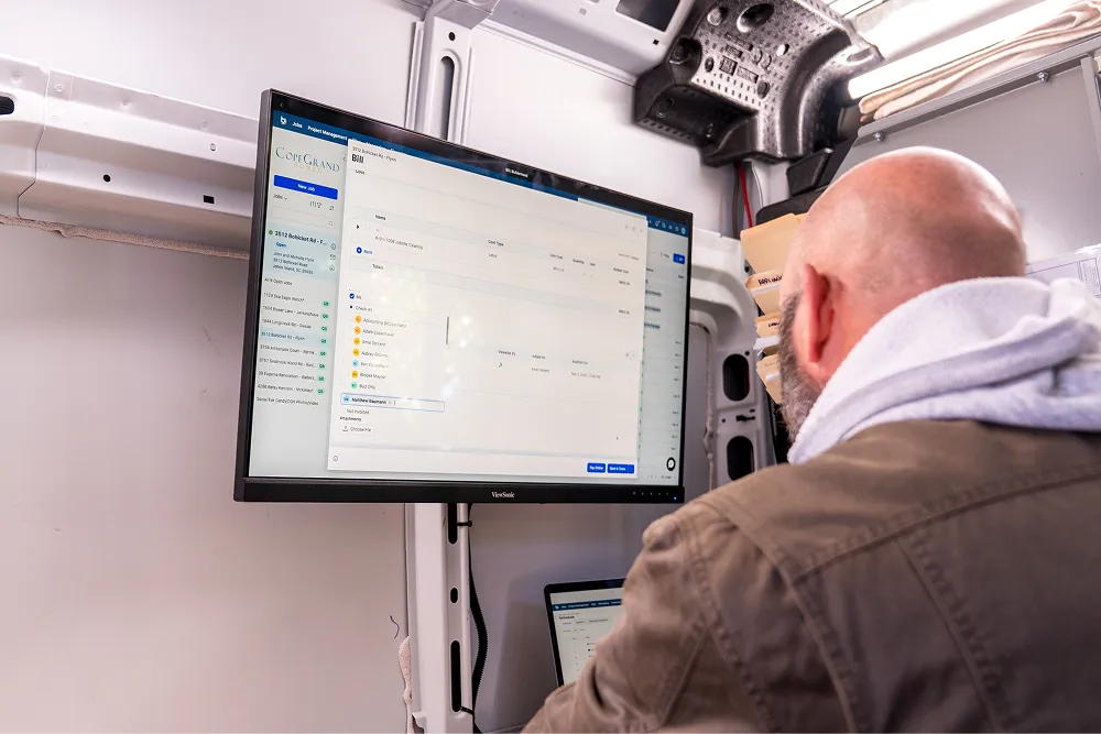 Man on job site looking at Buildertrend software on monitor