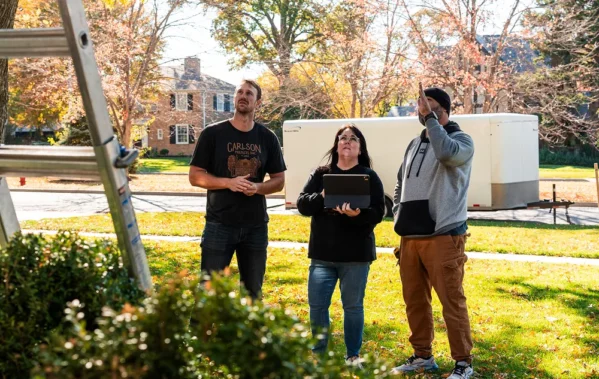 Three team members standing on the front yard looking up