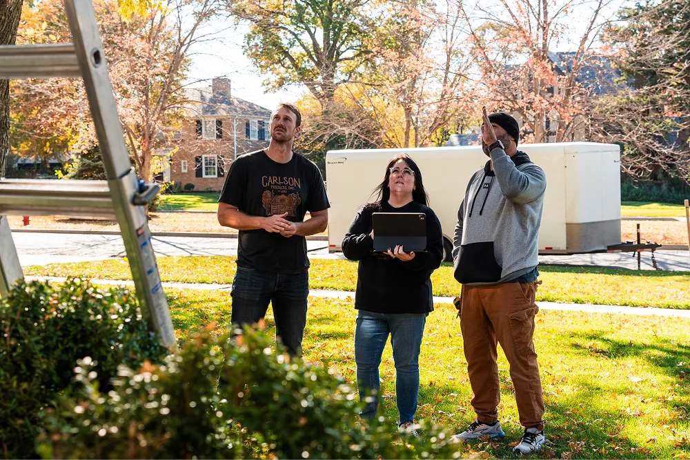 Three team members standing on the front yard looking up