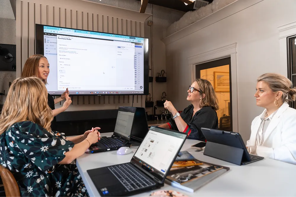 A group of women in a meeting room looking at Buildertrend product screen on a large monitor