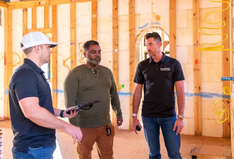 Three men conversing inside a framed home