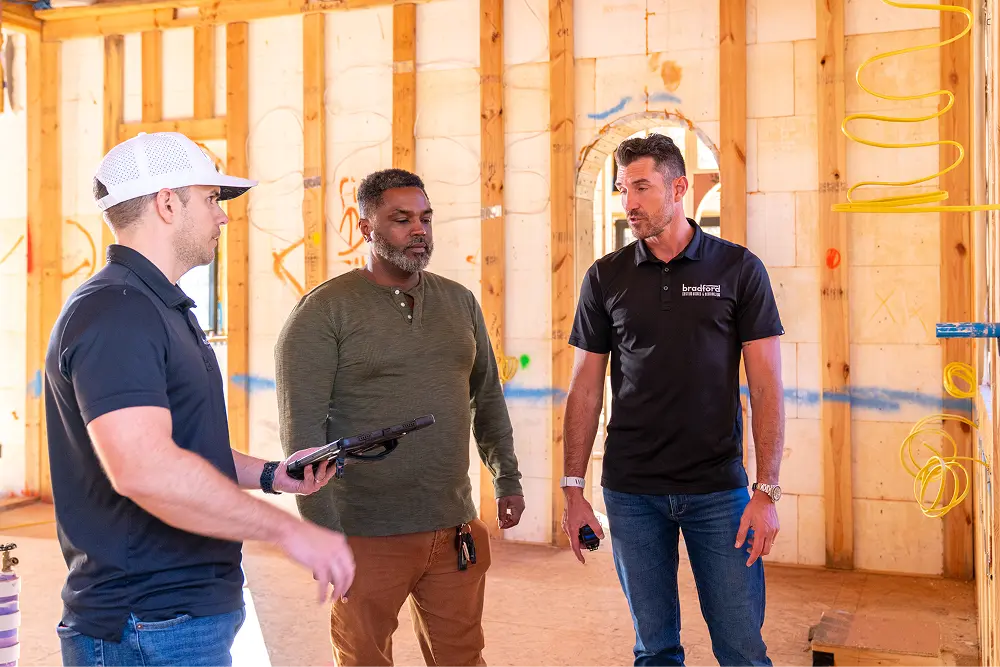 Three men conversing inside a framed home