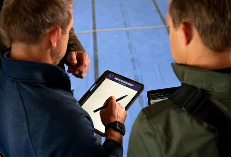 Construction professionals reviewing project information on tablets during a jobsite meeting.