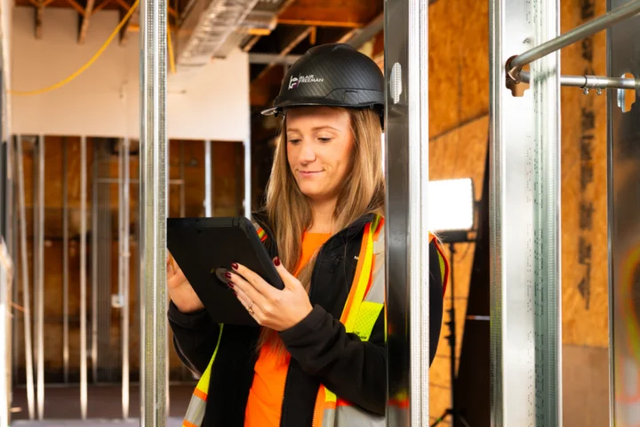 Construction professional using a tablet to review project information on an active jobsite.