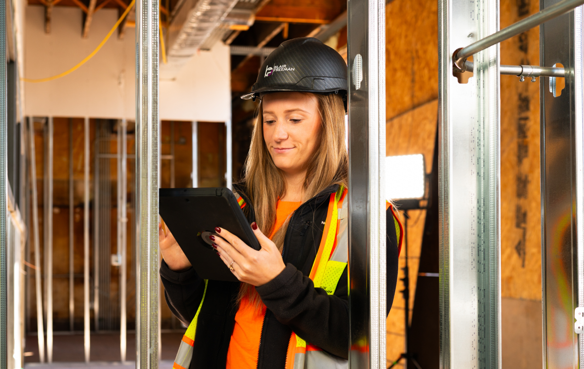 Construction professional using a tablet to review project information on an active jobsite.