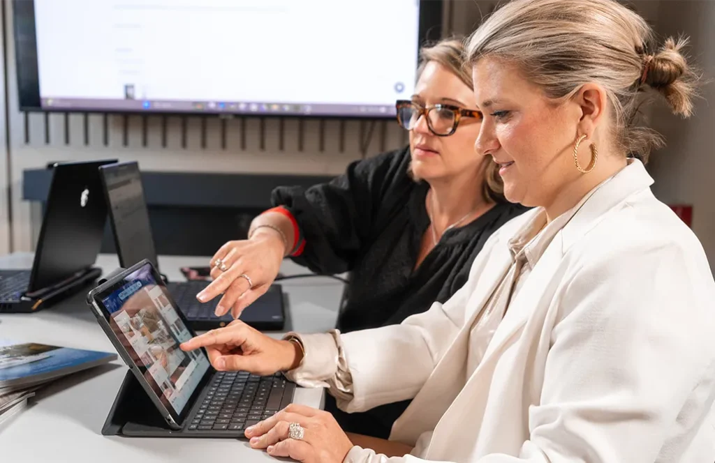 Two women reviewing interior design images together on a tablet in an office