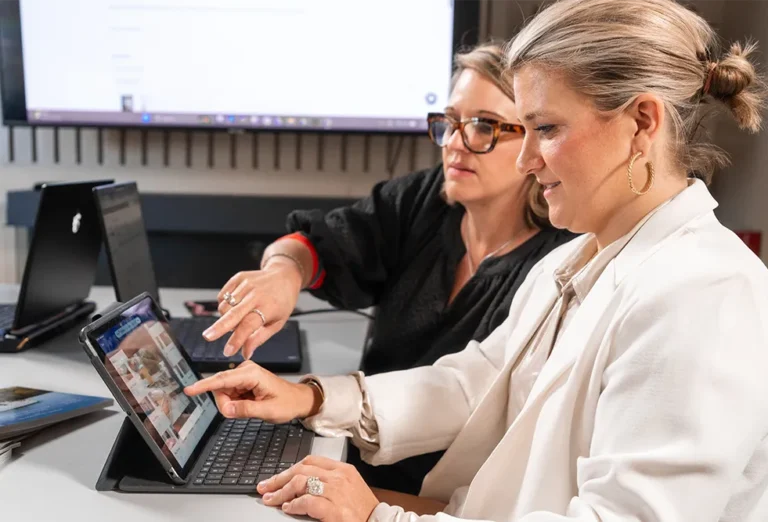 Two women reviewing interior design images together on a tablet in an office