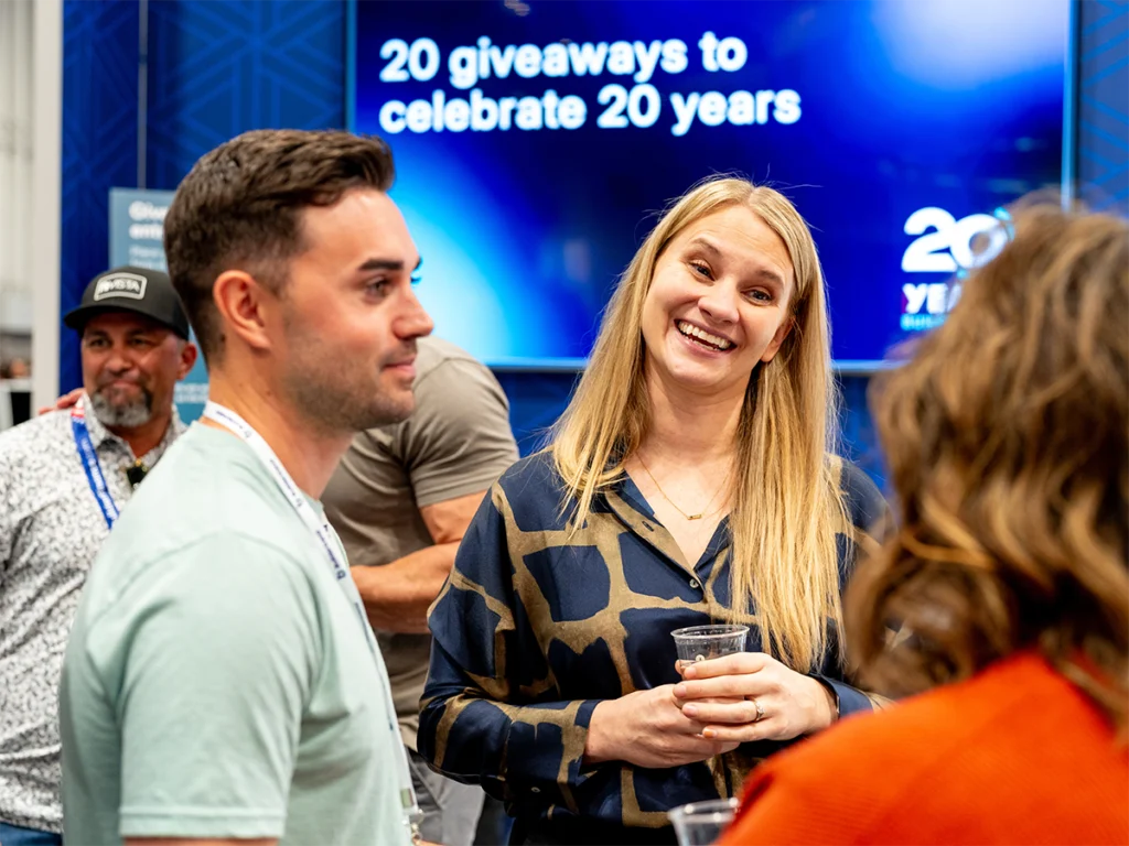 IBS 2027 7 International Builders' Show attendees networking at the Buildertrend booth during the company's 20th anniversary celebration.