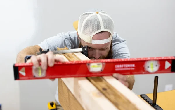 Man using a spirit level to check the alignment of clamped wooden boards