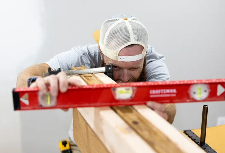 Man using a spirit level to check the alignment of clamped wooden boards