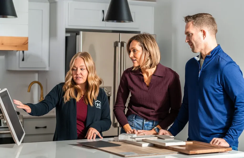 Three construction sales team members looking at a screen in home kitchen